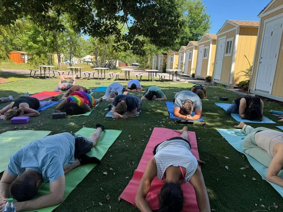Outdoor group yoga workshop with participants resting in child's pose on mats
